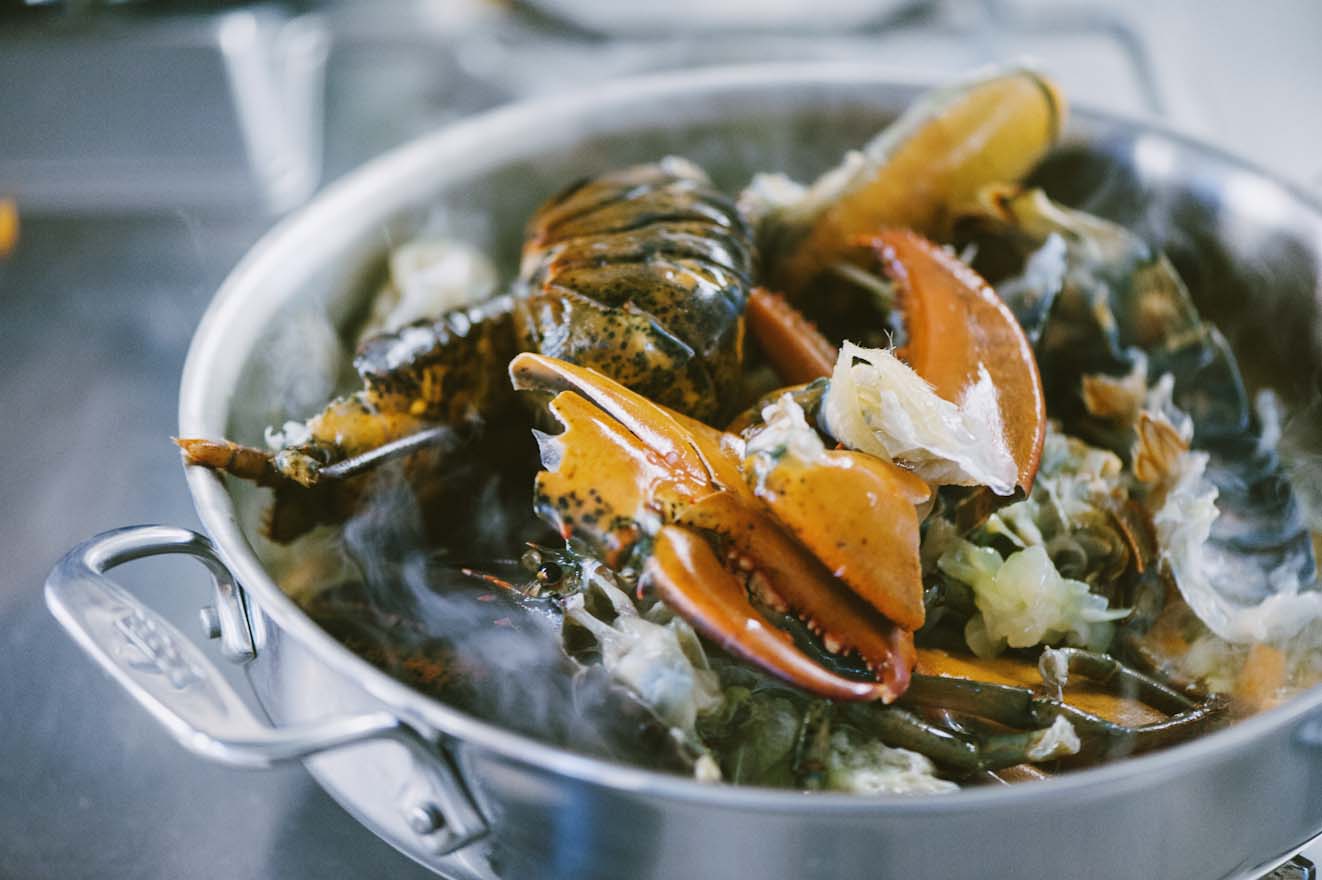 Chele e carapace di astice che rosolano con cozze e verdure nella casseruola fumante