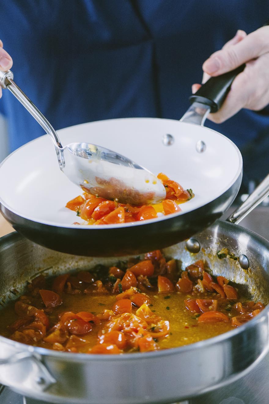 Un mestolo di sugo di pomodorini viene trasferito in una padella più piccola