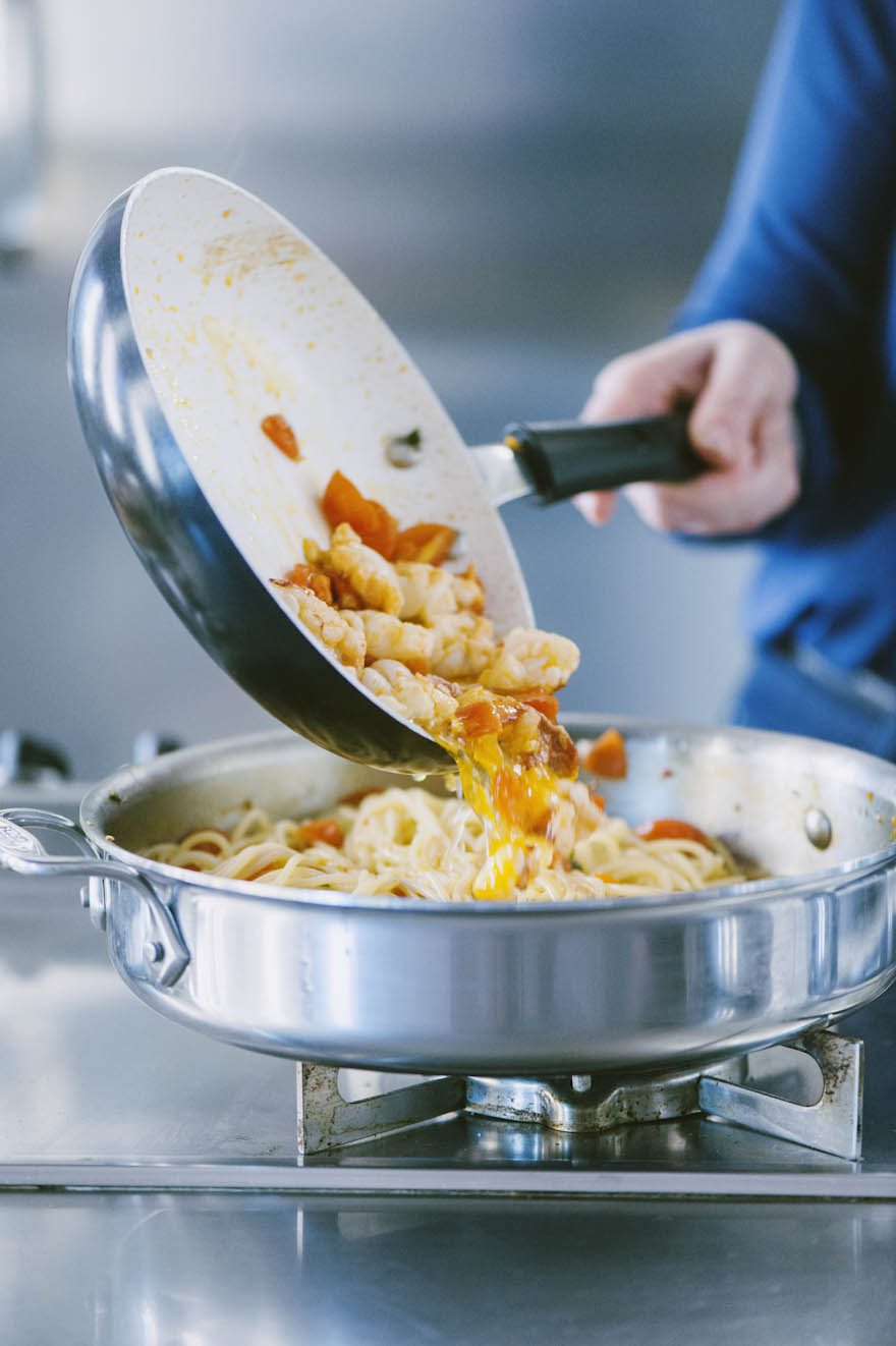 Polpa di astice con pomodoro versata sugli spaghetti ancora in cottura