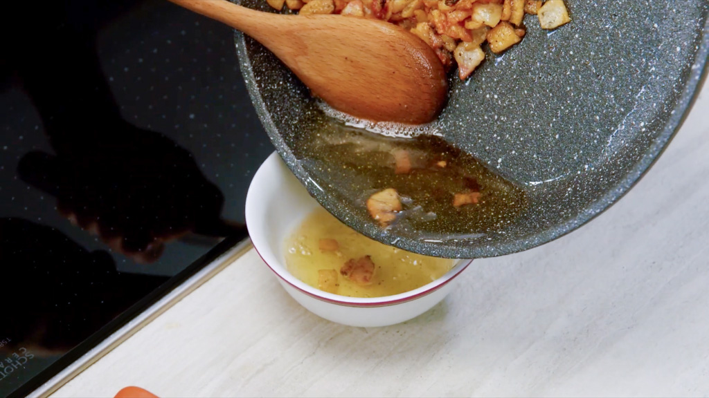 Grasso di cottura del guanciale versato dalla padella in una ciotola