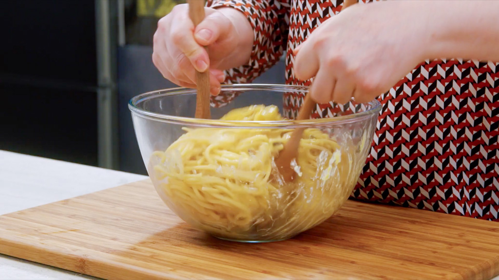 Spaghetti mantecati con la crema di uova e pecorino mescolati con due cucchiai di legno