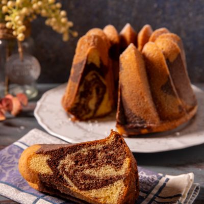 Ciambella marmorizzata con una fetta tagliata che mostra la spirale di cacao e impasto chiaro
