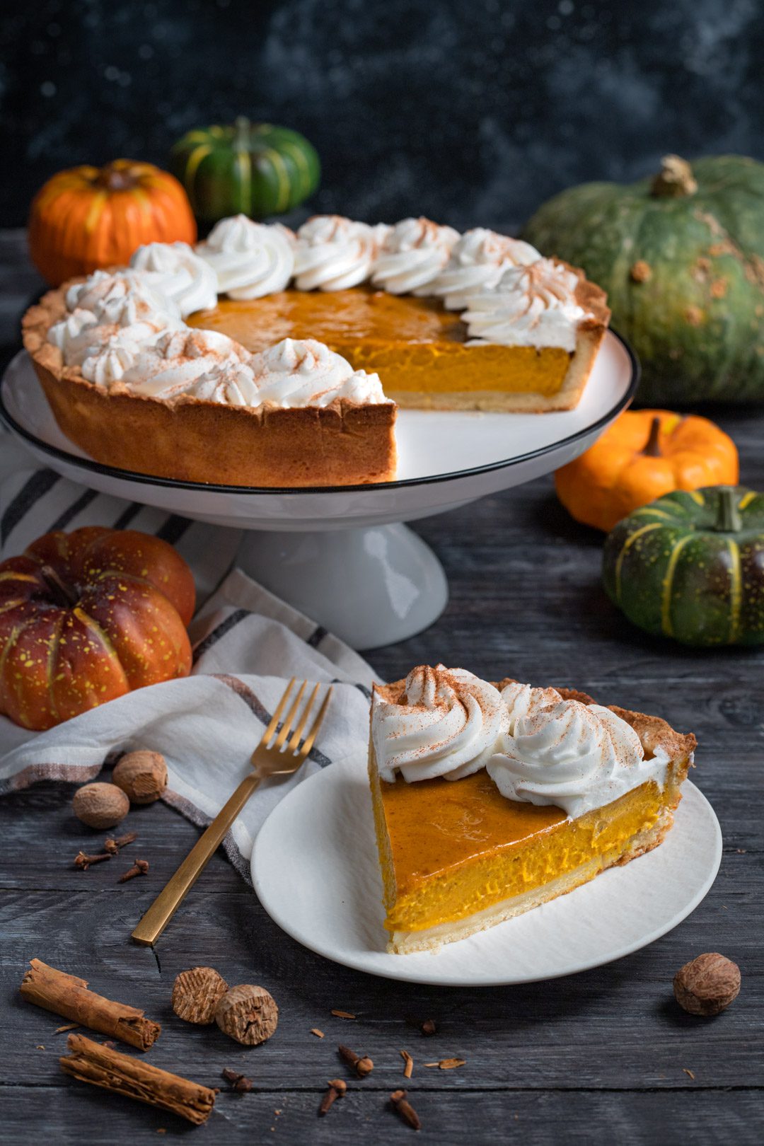 Fetta di pumpkin pie con ripieno di zucca e ciuffi di panna montata spolverati di cannella