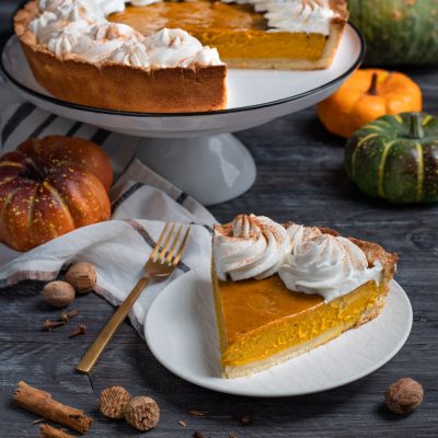 Pumpkin pie con ripieno di zucca e ciuffi di panna montata spolverati di cannella