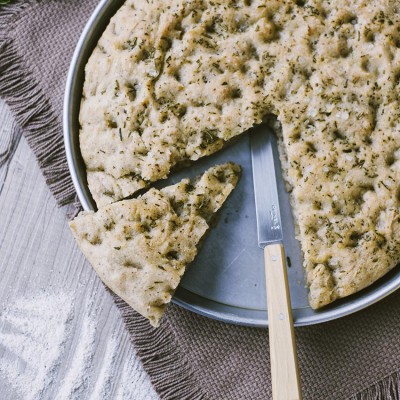 Focaccia senza glutine al grano saraceno con rosmarino, una fetta staccata e coltello