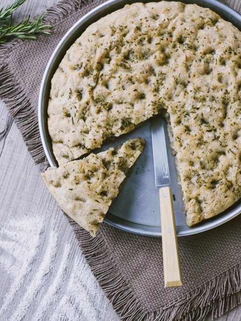 Focaccia senza glutine al grano saraceno con rosmarino, una fetta staccata e coltello