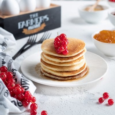 Pancakes allo sciroppo d'acero impilati e guarniti con ribes rosso fresco