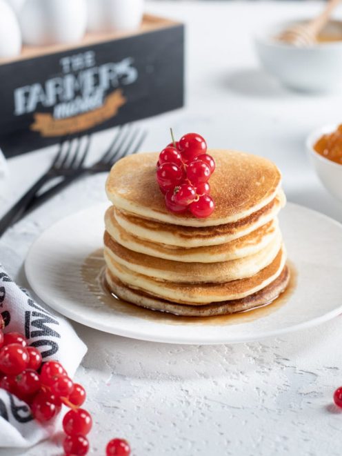 Pancakes allo sciroppo d'acero impilati e guarniti con ribes rosso fresco