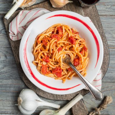 Pici all'aglione conditi con sugo di pomodoro a pezzi, serviti con forchetta