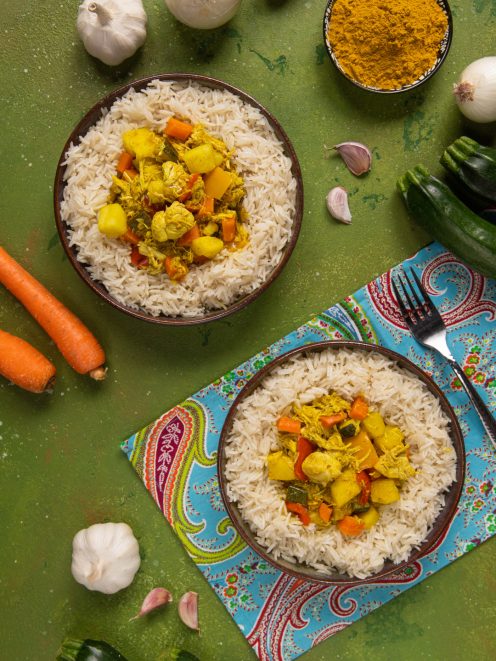 Pollo al curry con verdure servito su riso basmati, con carote, zucchine e patate al curry