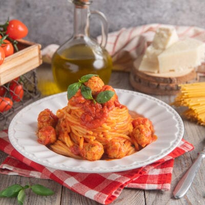 Spaghetti con le polpettine al sugo di pomodoro, guarniti con foglie di basilico fresco