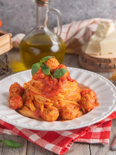 Spaghetti con le polpettine al sugo di pomodoro, guarniti con foglie di basilico fresco