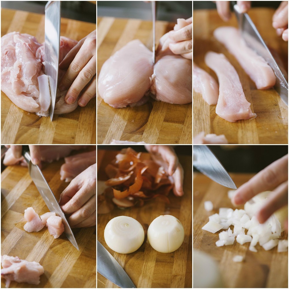 Petto di pollo tagliato a cubetti sul tagliere, con cipolla tritata e spicchi d'aglio sbucciati