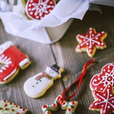 Biscotti di Natale decorati con glassa rossa e bianca a forma di pupazzo di neve, fiocco di neve e alberello
