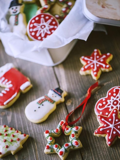 Biscotti di Natale decorati con glassa rossa e bianca a forma di pupazzo di neve, fiocco di neve e alberello