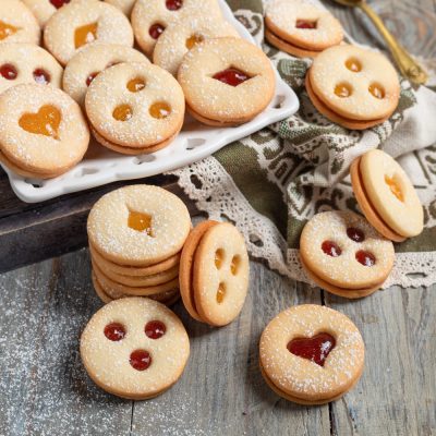 Biscotti tirolesi farciti con marmellata rossa e albicocca, finestre a cuore e rombo, spolverati di zucchero a velo