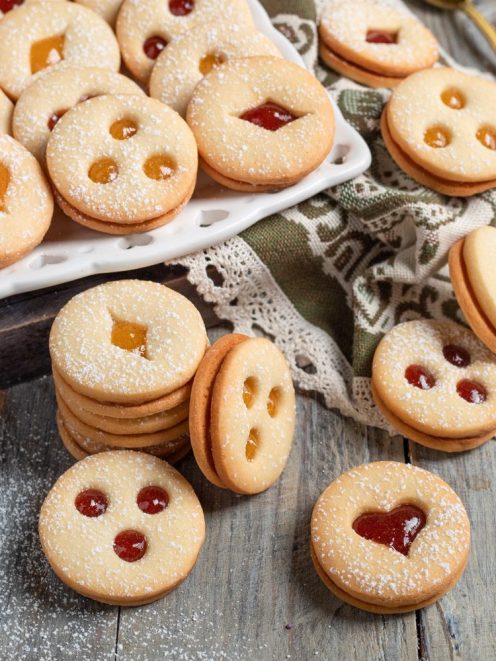 Biscotti tirolesi farciti con marmellata rossa e albicocca, finestre a cuore e rombo, spolverati di zucchero a velo