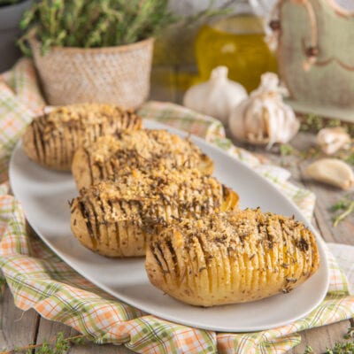 Patate Hasselback al forno con crosta di pangrattato ed erbe aromatiche, servite su vassoio