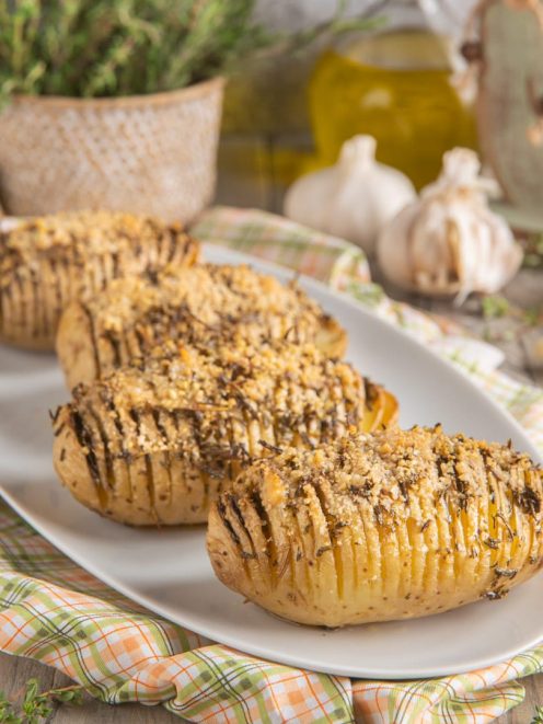 Patate Hasselback al forno con crosta di pangrattato ed erbe aromatiche, servite su vassoio