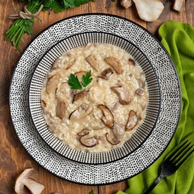 Risotto ai funghi porcini cremoso con fette di fungo ben visibili e una foglia di prezzemolo