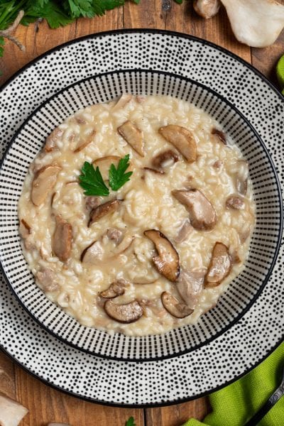 Risotto ai funghi porcini cremoso con fette di fungo ben visibili e una foglia di prezzemolo