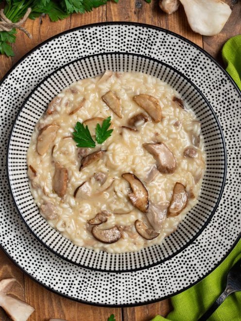 Risotto ai funghi porcini cremoso con fette di fungo ben visibili e una foglia di prezzemolo