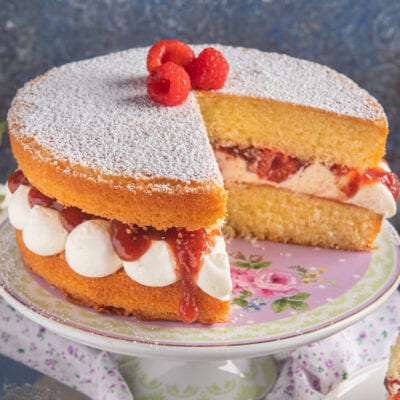 Victoria Sandwich farcita con panna e marmellata, spolverata di zucchero a velo e lamponi freschi