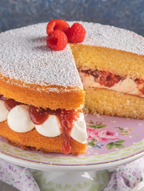 Victoria Sandwich farcita con panna e marmellata, spolverata di zucchero a velo e lamponi freschi