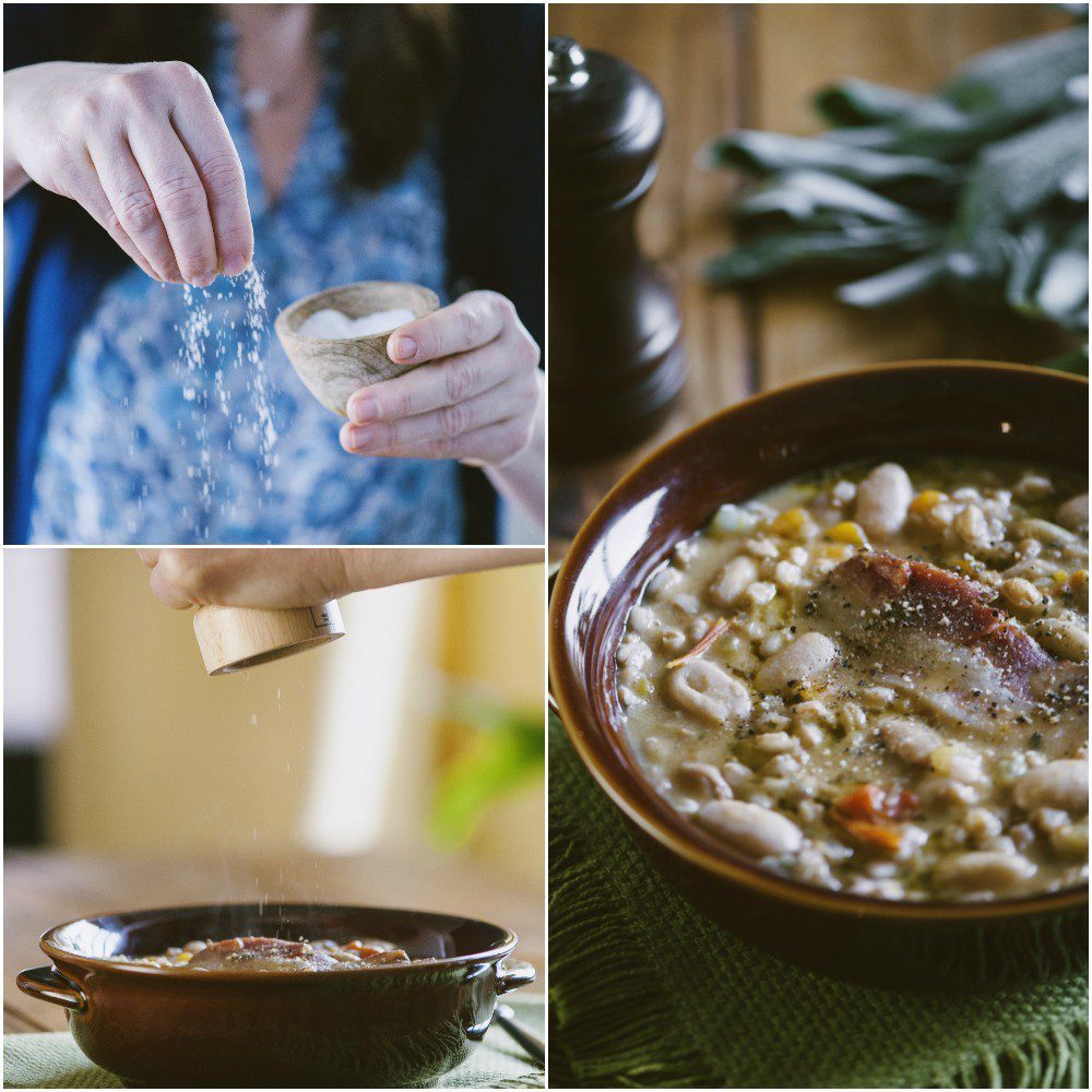 Sale e pepe aggiunti a mano sulla zuppa di farro e fagioli prima di servire
