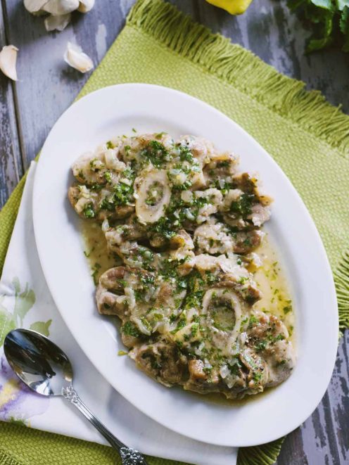 Ossobuco alla milanese con gremolata di prezzemolo, aglio e limone su vassoio da portata