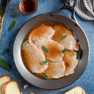 Scaloppine al marsala in padella con foglie di salvia e fondo di cottura lucido
