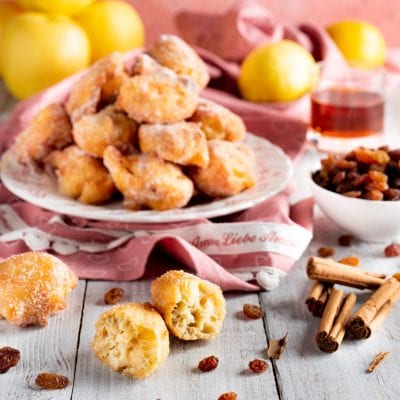 Tortelli di mele e uvetta fritti e spolverati di zucchero, uno spezzato mostra la morbida farcitura