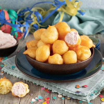 Tortelli salati al formaggio ripieni ammucchiati, uno aperto mostra la farcia cremosa rosa