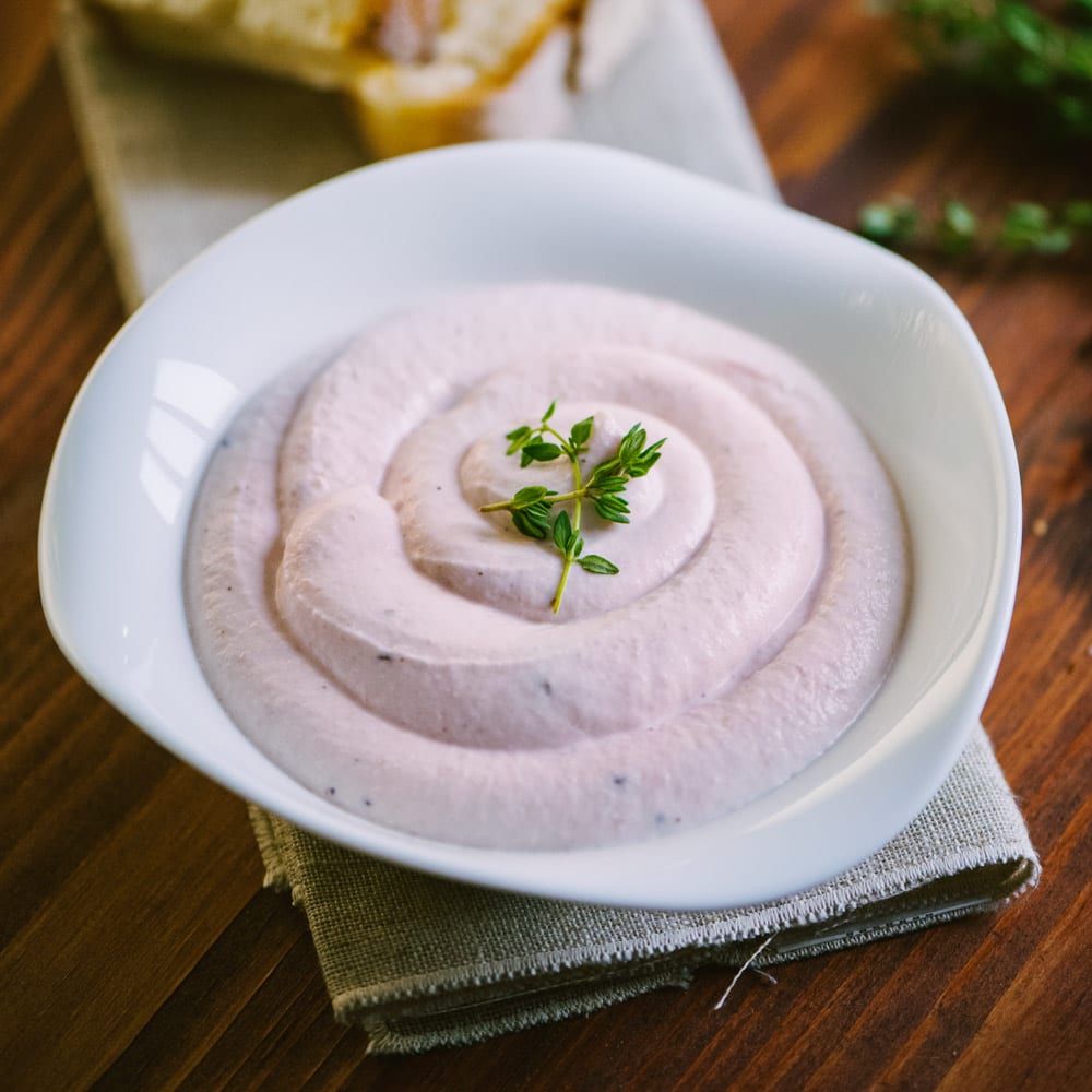Crema al prosciutto a spirale guarnita con un rametto di timo fresco
