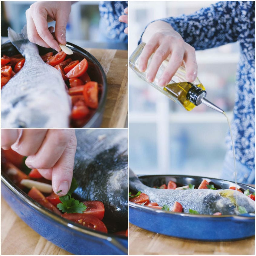 Mani che farciscono un'orata con aglio e pomodori, poi aggiungono prezzemolo e olio d'oliva