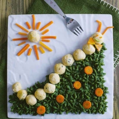 Bruco di polpette su prato di spinaci con rondelle di carota e sole decorativo