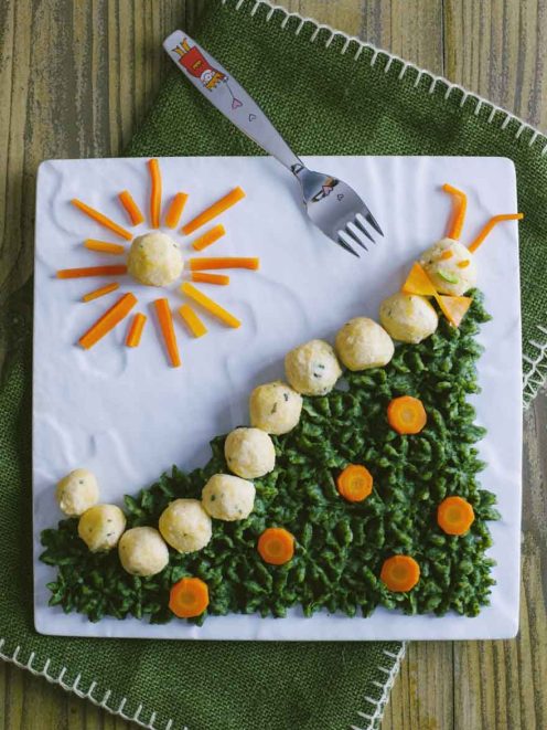 Bruco di polpette su prato di spinaci con rondelle di carota e sole decorativo