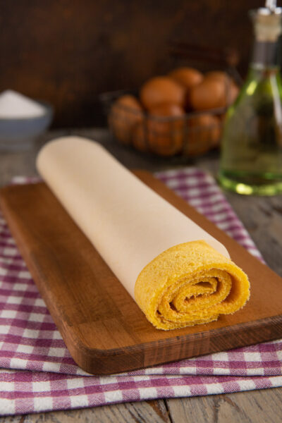Pasta biscotto all'olio arrotolata con carta forno, pronta per essere farcita
