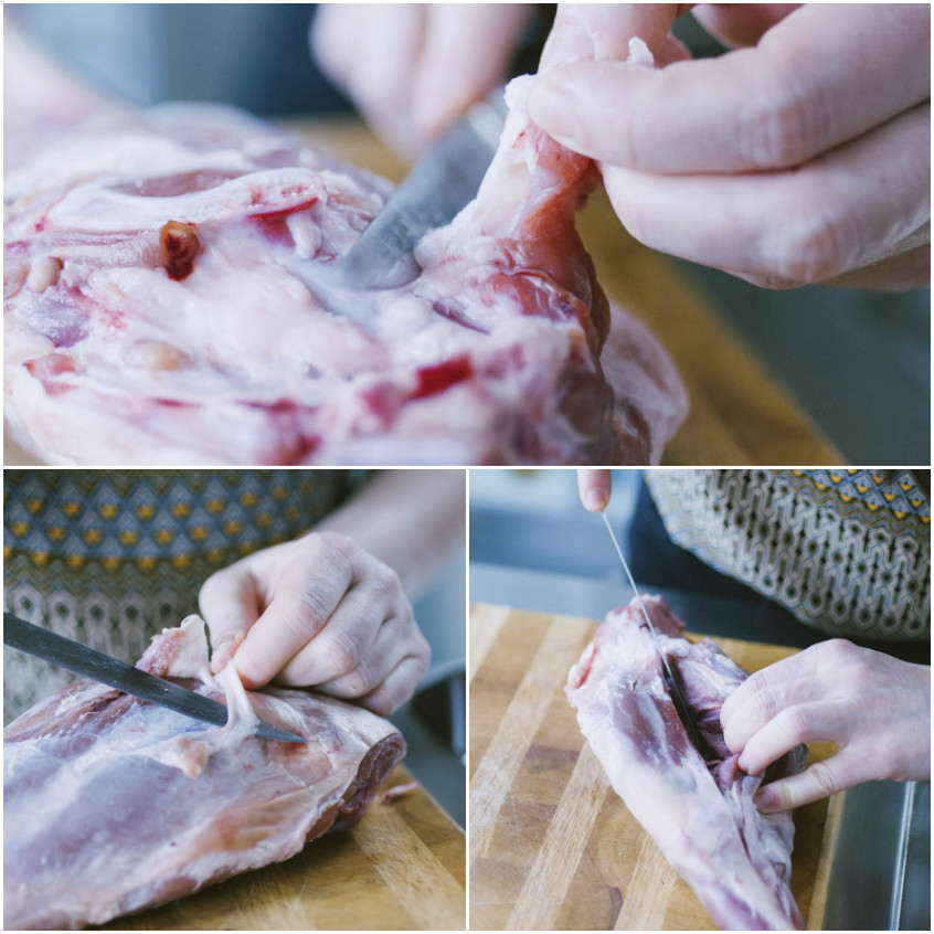 Mani che puliscono e disossano un cosciotto crudo con un coltello sul tagliere