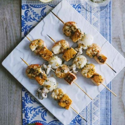 Spiedini di pesce con gamberi, calamari e salmone grigliati, conditi con erbe aromatiche