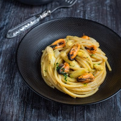 Bigoli con asparagi e cozze conditi con prezzemolo tritato e serviti in nido