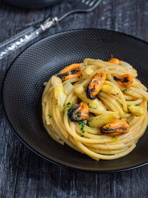 Bigoli con asparagi e cozze conditi con prezzemolo tritato e serviti in nido