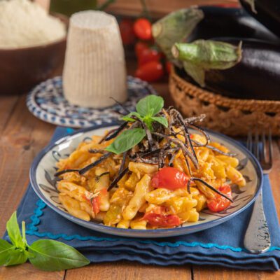 Cicatielli con pomodorini e melanzane, guarniti con strisce di melanzana fritta e foglie di basilico