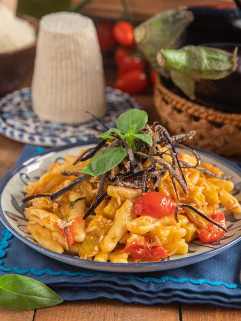 Cicatielli con pomodorini e melanzane, guarniti con strisce di melanzana fritta e foglie di basilico