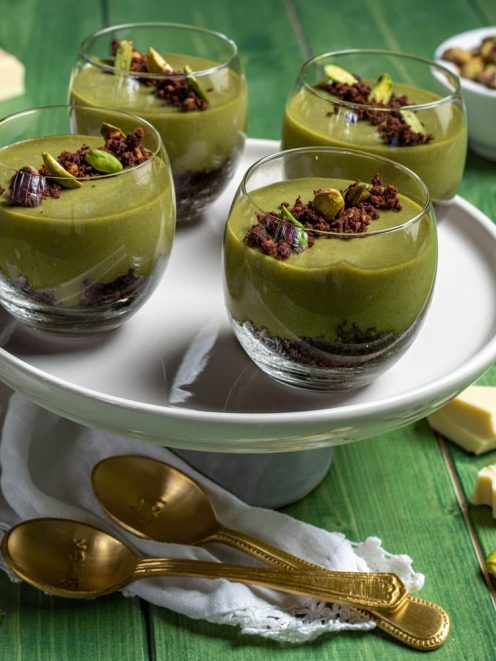Cremoso al pistacchio e cioccolato bianco in bicchieri con base di sbriciolato al cacao e granella di pistacchi