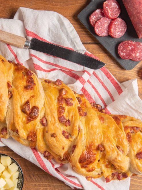 Treccia salata intrecciata e dorata al forno con salame e formaggio in superficie