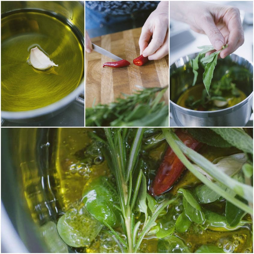 Olio extravergine che sobbolle con aglio, peperoncino a metà ed erbe aromatiche fresche