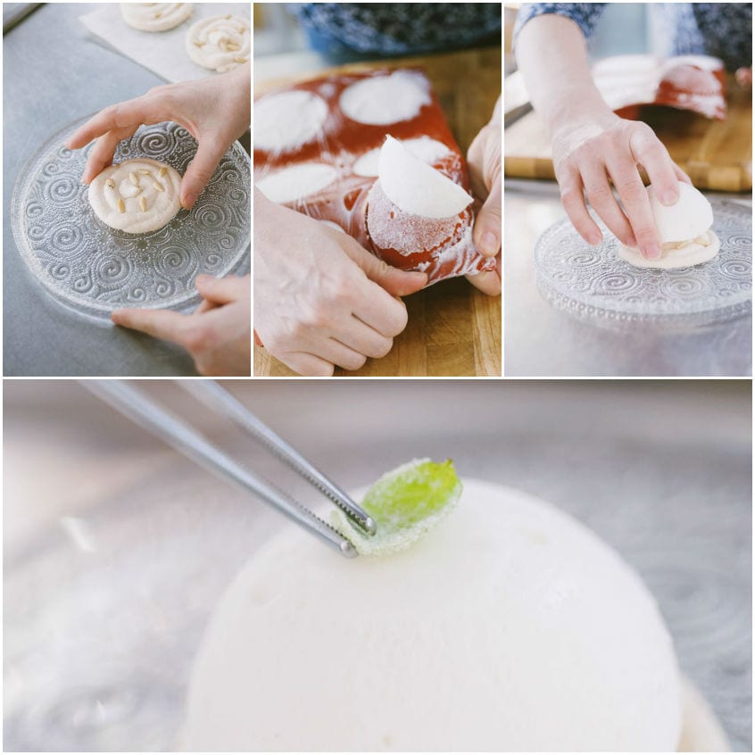Mani che assemblano il dessert: biscotto ai pinoli, semisfera di gelato e fogliolina di basilico cristallizzata con pinzette