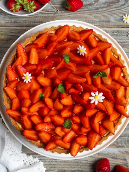 Crostata alle fragole con fette lucide di frutta fresca, crema e decorazioni di menta