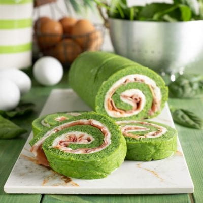 Rotolo di frittata agli spinaci affettato mostra la spirale di stracchino e speck